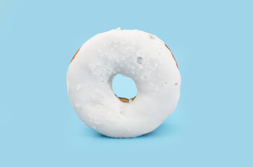 donut with white chocolate icing isolated on blue background.