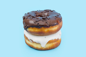 Two delicious donuts with black and white chocolate icing isolated on a blue background.