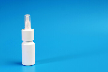 white nasal spray bottle on blue background with a copy space