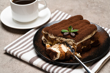 portion of Classic tiramisu dessert and cup of fresh espresso coffee on concrete background