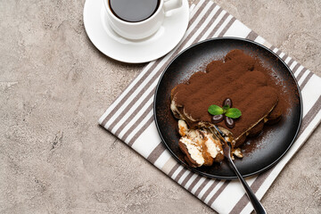 portion of Classic tiramisu dessert and cup of fresh espresso coffee on concrete background