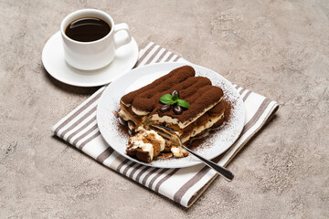 portion of Classic tiramisu dessert and cup of fresh espresso coffee on concrete background