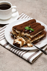 portion of Classic tiramisu dessert and cup of fresh espresso coffee on concrete background