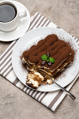 portion of Classic tiramisu dessert and cup of fresh espresso coffee on concrete background