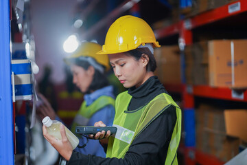 Female asian warehouse worker standing with barcode scanner.