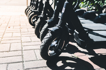 Electric scooters stand in a row on the road in a park area. Modern transport for recreation and entertainment © nazarioking