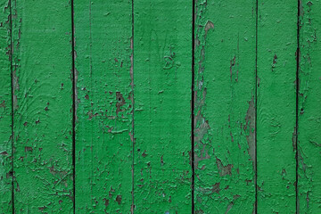 The texture of the wall is made of old boards painted with green paint, peeling from time. Building, structure with signs of aging.