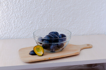A transparent bowl with juicy plums