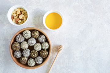 Obraz na płótnie Canvas Healthy vegetarian balls with cashews, hazelnuts, peanut butter and almond with honey in the clay bowl on the light background. Vegetarian, organic food. Flat lay with copy space.