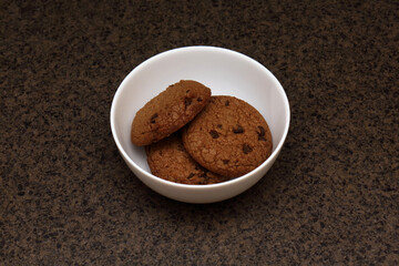 Oatmeal cookies with chocolate pieces in white bowl