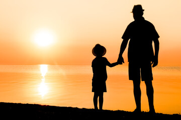 A Happy parent with child by the sea play on nature silhouette travel