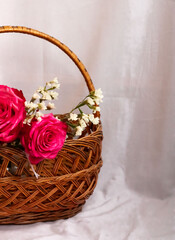 Fototapeta na wymiar Basket with pink and white flowers on a light background.