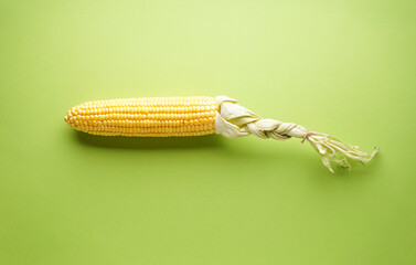 Ear of ripe corn on a green background, flat lay.