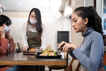 New normal customer dine in restaurant. Waitress with mask serve food.