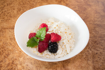 Healthy morning breakfast. Fresh cottage cheese with raspberries, blackberries and a mint leaf in a white plate. Protein breakfast option for weight loss and weight loss.