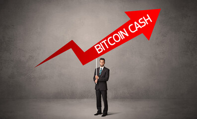 Fototapeta premium Young business person in casual holding road sign with BITCOIN CASH inscription, business direction concept
