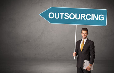 Young business person in casual holding road sign with OUTSOURCING inscription, new business direction concept