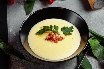 bowl of tasty cheese cream soup with bacon on a gray background