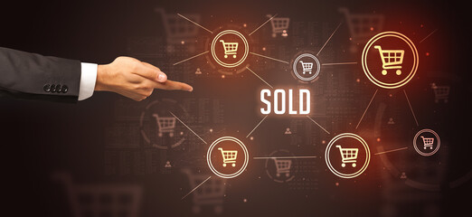 Close-Up of cropped hand pointing at SOLD inscription, online shopping concept