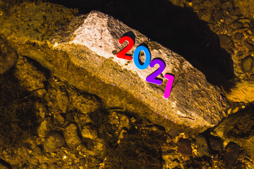 numbers of different colors new year 2021 on a stone among the water