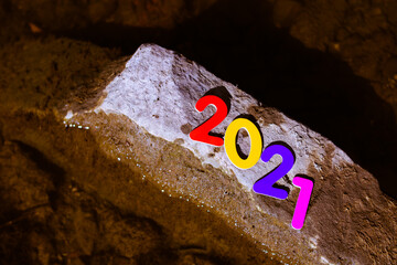 2021 new year numbers in different colors on stone and water background