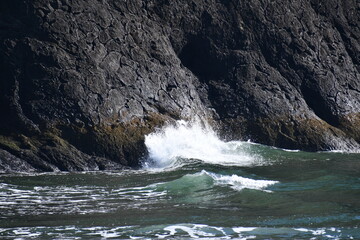 Wave crashes upon cliff-side.