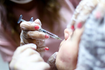 Close-up photo of a young girl injecting cosmetic procedure.