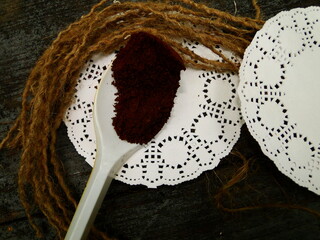 ground black coffee in a white spoon on a round shaped napkin