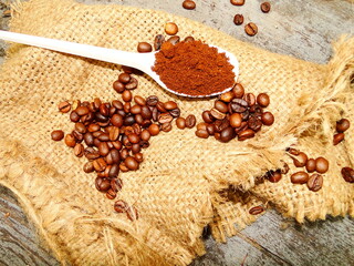 ground coffee in a white spoon on a burlap bag with scattered coffee beans