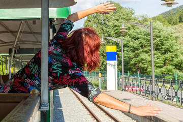 Parte trasera de mujer, dentro de un tren con los brazos abiertos saludando