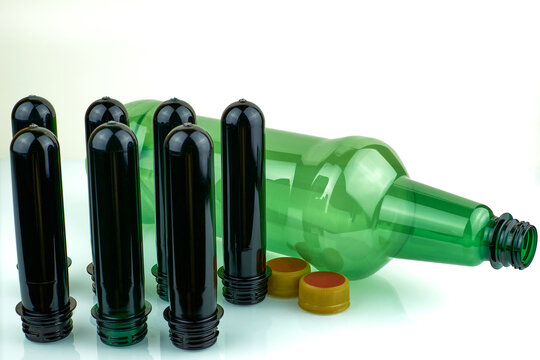 PET Preforms And Plastic Bottle On White Background. Brown And Green PET Preforms For Plastic Bottles.