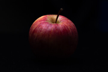 One red fresh apple on a black background. Healthy fruit and breakfast.