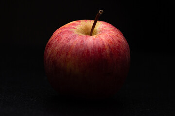 One red fresh apple on a black background. Healthy fruit and breakfast.