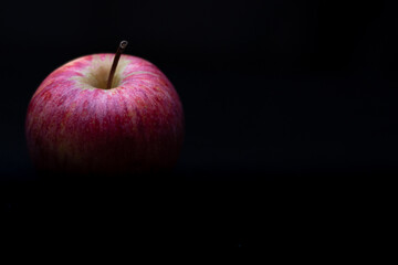One red fresh apple on a black background. Healthy fruit and breakfast.