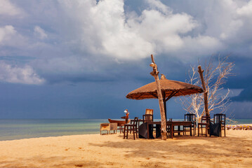 Wooden chairs and umbrellas on white sand beach