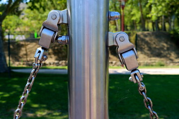 Metal constructions with bolts and iron shiny thick chains for attaching the swing. Metal chain of...
