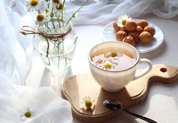  A Cup of fragrant chamomile tea with a delicate bouquet of daisies close - up-the concept of a pleasant tea party and pastime.