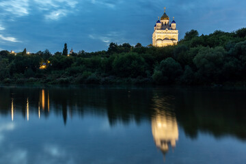 Fototapeta na wymiar Russia, the city of Yelets, view of the high Bank of the Sosna river and the Cathedral of the ascension of the Lord with the reflection in the water at dusck