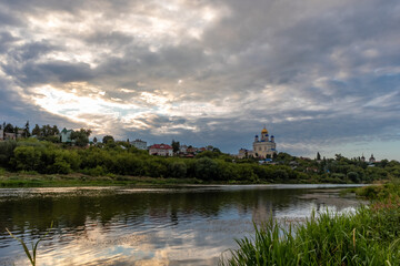 Fototapeta na wymiar Russia, the city of Yelets, view of the Sosna river and the Cathedral of the ascension of the Lord under a cloudy sunset sky.