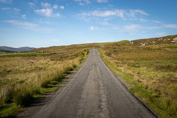 Fototapeta na wymiar Straight single track road with turns at the end in Scottish Highlands, UK. Beautiful summer sunny day
