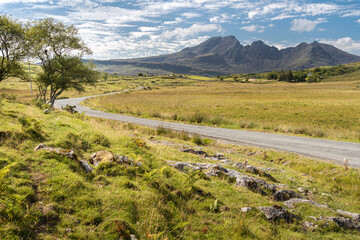 Scenic view of Bla Bheinn mountain (also known as Blaven) in Black Cuillin ridge, Isle of Skye, Scotland. Beautiful summer sunny day and single track road leading towards mountains