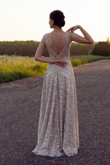 A girl in an evening dress with an open back. The girl is standing back, she is dressed in a long...