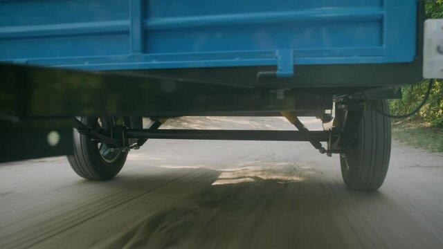 A small cargo trailer for a car on the move. View of the cross member of the wheelbase from below and extremely close.