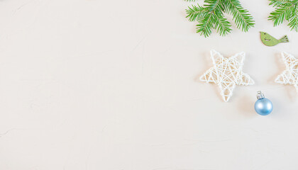 New Year and Christmas flat lay in pastel neutral colors: wooden decorative stars, fir branches, wooden figurines of birds, Christmas tree toy ball on light background. Copyspace, minimalism, top view