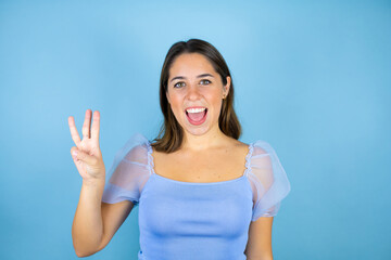 Fototapeta premium Young beautiful woman over isolated blue background showing and pointing up with fingers number three while smiling confident and happy