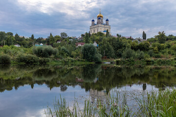 Fototapeta na wymiar Russia, the city of Yelets, view of the high Bank of the Sosna river and the Cathedral of the ascension of the Lord under a cloudy sunset sky.