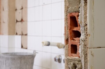 Pared rota de azulejos con ladrillos en el interior