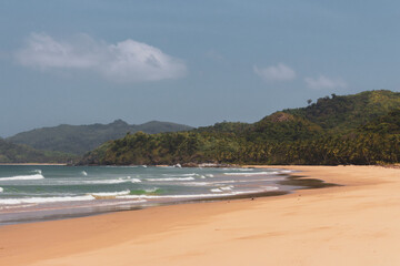 Empty tropical beach on sunny day. Duli beach in Palawan, Philippines. Surf beach. Wide beach with island on background. Travel in Asia. Tropical landscape. Azure water in idyllic lagoon. 