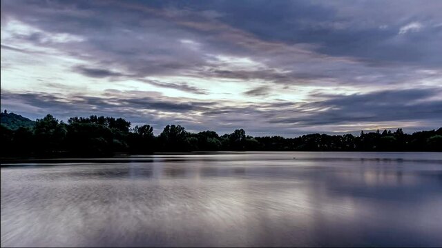 Clouds rolling over Westport lake in Stoke on Trent, Staffordshire, UK at sunset.Day to night 4K time-lapse video clip.Tranquil evening landscape scene.