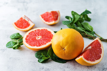 Red grapefruit with slaces and mint leaves on a light background